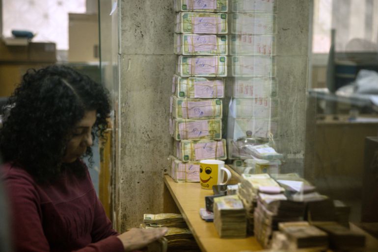 DAMASCUS, SYRIA - DECEMBER 24: An employee works in front of stacks of Syrian pounds at the exchange department at the Central Bank Of Syria on December 24, 2024 in Damascus, Syria. On December 8, rebel forces in Syria retook the capital and several other cities from longtime ruler Bashar al-Assad, who fled the country for Moscow. The fall of the Assad regime marks a new chapter for Syria, which has been mired in a multi-party civil war since 2011, sparked by the Arab Spring uprisings. (Photo by Chris McGrath/Getty Images)