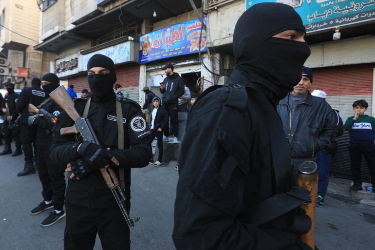 Security forces reporting to Syria's transitional government stand guard on a main street in Dummar, a suburb of the Syrian capital Damascus, during an operation to seize weapons and hunt down armed supporters of the ousted Assad leadership on January 15, 2025. The Syrian Observatory for Human Rights reported earlier this month that fighters linked to the Islamist-led transitional administration publicly executed the former mayor of Dummar on January 10, accusing him of having been an informant under ousted president Bashar al-Assad. (Photo by Bakr ALKASEM / AFP)